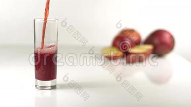 在苹果模糊的背景下，空杯子里满是红色的果汁。