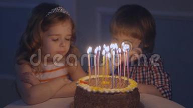 一个小男孩和一个<strong>女孩</strong>在一个庆祝蛋糕上看<strong>许愿</strong>，然后在蛋糕上吹蜡烛