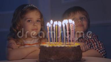 一个小男孩和一个女孩在一个庆祝蛋糕上看<strong>许愿</strong>，然后在蛋糕上吹蜡烛