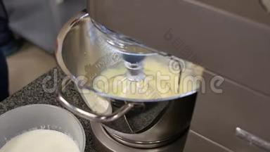 奶油和搅拌器。 烹饪，用电动搅拌器搅拌鸡蛋。 将蛋奶油搅拌入搅拌机碗中