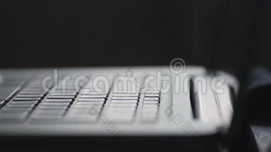 现代笔记本电脑键盘上的手轴。 手指键入文本。 关门