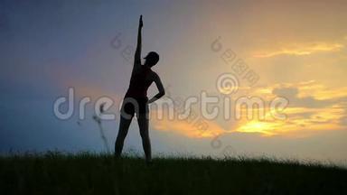 运动员在一个女孩的日落剪影上做运动