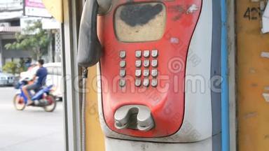旧的破旧的红色电话设置在一条城市街道上。 电话亭里的老式电话