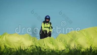 滑翔伞女孩。 滑翔伞准备在一座绿色的小山上起飞。