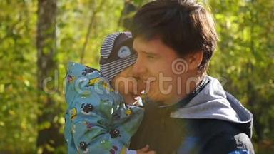 年轻的<strong>父亲</strong>在秋天公园的特写镜头中<strong>温柔</strong>地和婴儿玩耍