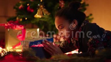 黑人少女在装饰圣诞树下打开圣诞礼物盒