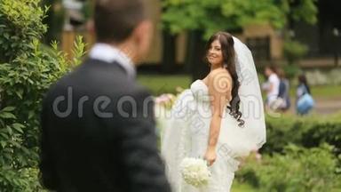 快乐的新婚新郎和新娘在夏季公园。 嬉戏的新娘召唤她慈爱的新丈夫