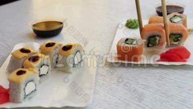 寿司是用中国棍子拿的，浸泡在酱油里。 美味的寿司和三文鱼、姜奶酪和芥末