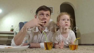男人和女儿看电视，坐在地上喝果汁