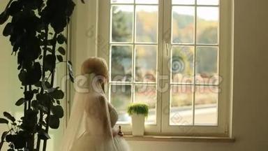 华丽时尚的金发新娘看着窗外，在古董房的背景下等待新郎