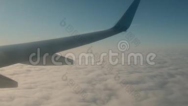 飞机的翅膀飞过云层，从窗户看。