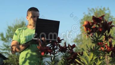 清晨，一个男人在花床旁的笔记本电脑上工作