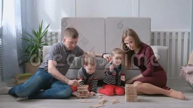 一家人的妈妈、爸爸和两个双胞胎兄弟一起在地板上用木块做游戏。