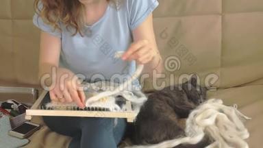 一个女人在织布机上织着一件由纱线制成的美丽刺绣，在一<strong>家家</strong>庭工作室里，猫在附近。
