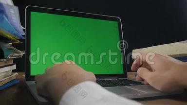 关闭人在笔记本电脑的后期办公室与绿色屏幕。 在电脑前工作的商人