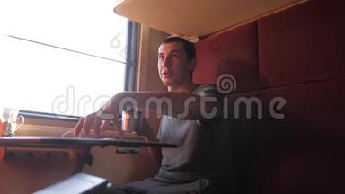 男人坐在火车车厢里，捧着咖啡喝茶。 慢动作视频。 男人