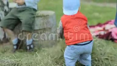 男孩和其他孩子和干草玩。 他捡起干草扔到另一个地方