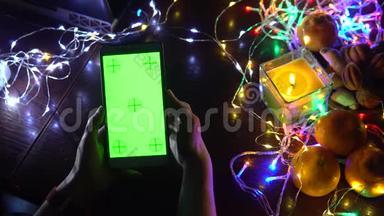 黑色背景桌子上的智能手机，五颜六色的灯光，圣诞新年作文。 智能手机游戏
