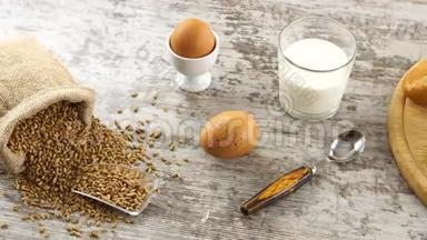 一堆小麦、牛奶、鸡蛋和新鲜的面包放在乡村的木桌上。 乡村早餐。