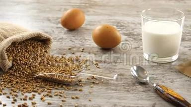 在一张乡村的木桌上放着小麦、牛奶、鸡蛋和新鲜面包。 乡村早餐。