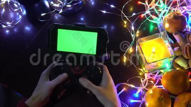 游戏垫与智能手机在黑色背景桌子与彩色灯，圣诞节新年作文。 智能手机游戏