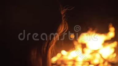 神秘女人黑色背景的剪影，火焰，火花，轮廓轮廓。 户外慢速运动