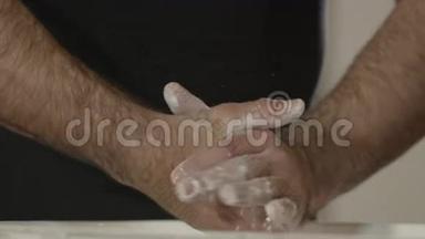 特写双手用白色粉笔粉拍手.. 运动员用滑石粉拍手