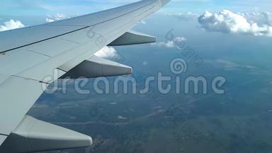 从飞机窗户上看到机翼、云层和地面，在云层上方飞行