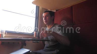 男人坐在火车车厢里，捧着咖啡喝茶。 慢动作视频。 男人