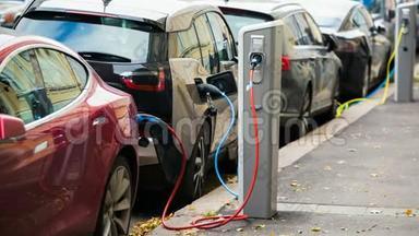 许多电动汽车在停车场由充电站充电。