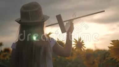 戴帽子的女孩玩木<strong>飞</strong>机。 快乐的孩子在日落时在向日葵田玩玩具<strong>飞</strong>机。 在