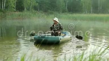 一个渔夫用桨在一艘充气船上航行。 清晨，水上有雾。 在野外度假。