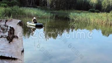 渔夫乘一艘<strong>充气船</strong>在河上漂浮。 摄像机从桦树上看出来。 野外活动