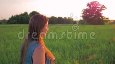 夕阳下，一头直发的小女孩走在一片绿色的田野上。 平均射击。 慢动作