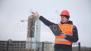 建筑设计师戴着头盔和橙色背心的工人，背景是一栋多层<strong>房屋冬季</strong>起重机