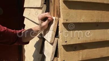 木工用锤子和钉子把木板钉在木墙上