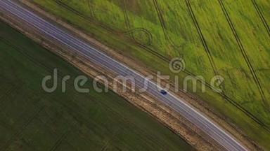 一辆汽车沿着两块田之间的乡村道路行驶的俯视图