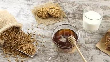 在一张乡村木桌上放着小麦、蜂蜜、牛奶、饼干和新鲜面包。 乡村早餐。