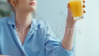 幸福的年轻女人在早餐时喝橙汁的肖像。