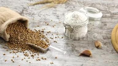 一小袋小麦，面粉，大蒜，和新鲜的面包在一个乡村的木制桌子上。