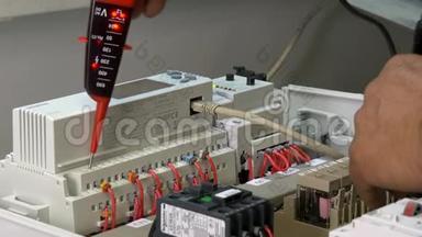 工人手检查工厂电子产品中的触点<strong>电压</strong>指示器。