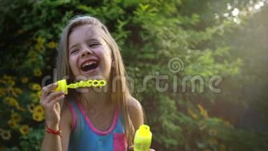 一个快乐的小白种人女孩在阳光明媚的日子里缓慢地吹着肥皂泡。 童年快乐或儿童概念