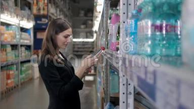 微笑的女人在超市的杂货店买了一瓶水，女商人在购物
