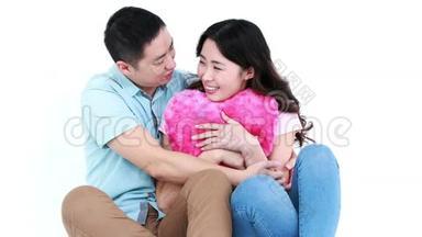 微笑的亚洲夫妇坐在一起拥抱枕头