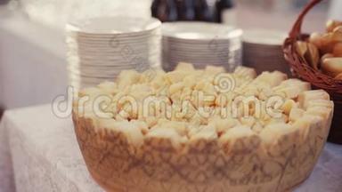 意大利菜肴摆在一个深木盘上，桌上放着白色盘子和一篮子饼干，优雅的仪式