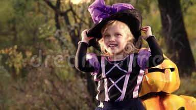 穿着女巫服装和南瓜杰克在一起的小女孩。 穿着万圣节女巫服装的滑稽女孩