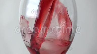 在灰色背景下将红酒倒入玻璃杯中，动作非常慢