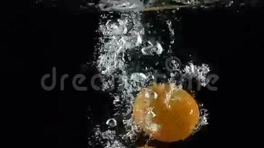 两个橘子在黑色背景下落入水中超级慢镜头