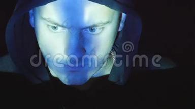 戴着头巾的黑客在电脑上工作，二进制代码投射在他的脸上。 对愤怒的敌对者的源代码