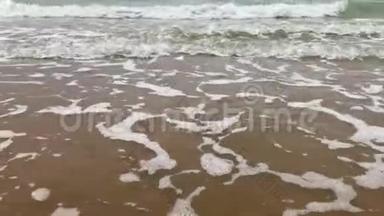 海水的泡沫在沙滩上的波浪中，阳光在海水中